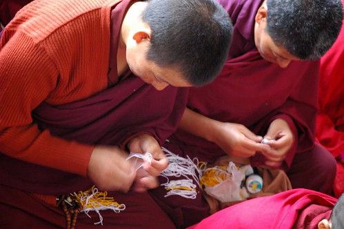 Two monks making blessing objects from string, Tharlam Monastery, Boudha, Nepal by Wonderlane