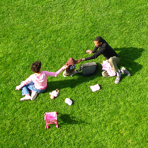 Parents and toddler on the grass in Paris, France.
