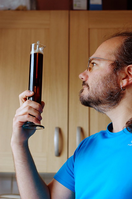 Wulf standing in front of a window holding up a sample tube of beer