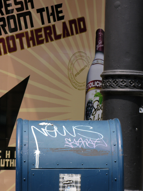 graffiti on a mailbox with Stoli vodka ad and a pillar in the background, Manhattan, NYC