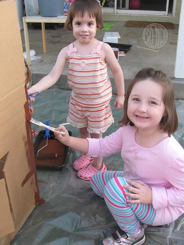 happy children painting large cardboard gingerbread house 