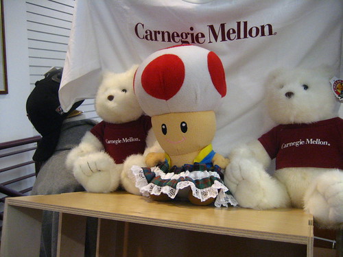 Toad is wearing a tartan garter sharing time with other plushes