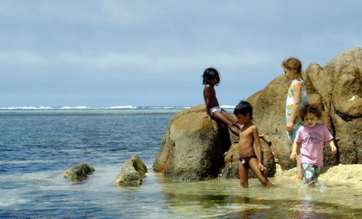 Local kids playing on granite rocks in Anse aux Courbes on Mahe (Seychelles)