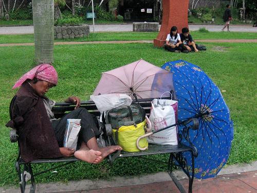  An homeless old woman rests on a bench in a public park in Luneta Park Manila Philippines Buhay Pinoy  Ngayon Filipino Pilipino  people pictures photos life Philippinen public park personal belongings homeless    