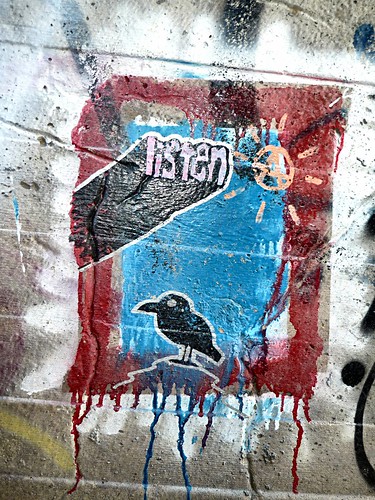 graffiti: a black bird in a blue window, with the word 'listen' pushing out overhead