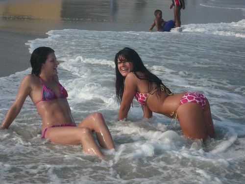 Two women on the beach wearing giraffe print bikinis
