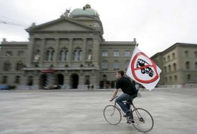 A man on a bicycle holds a flag protesting against off-road cars, in front of the parliament building in Bern 