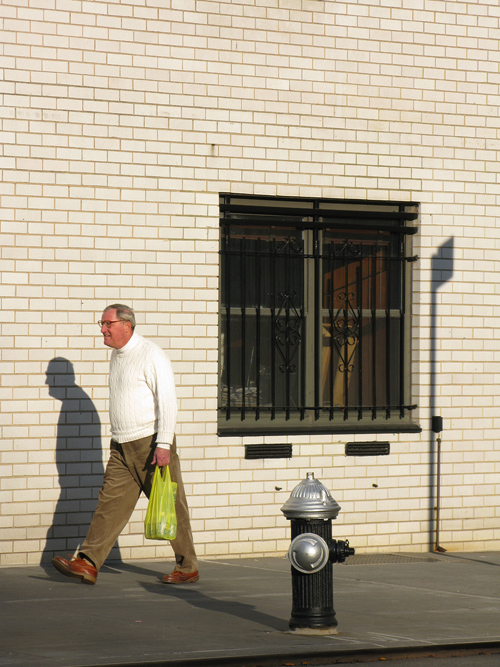 a man walks on a Manhattan sidewalk, NYC