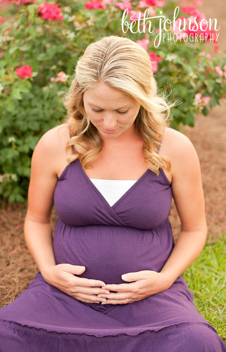 maternity photography in front of pink flowers purple dress