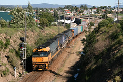 Pacific National diesel electric locomotives NR20 + NR57 + NR112 work a down container freight train pass the tiny railway station at Telerah, N.S.W. Australia.