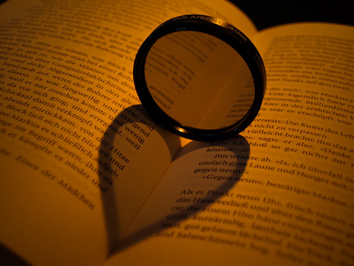 Heart shaped shadow cast over a book by a round lens