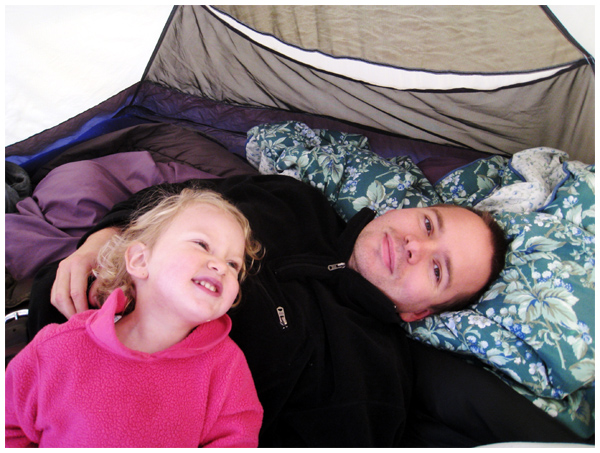 Father and daughter laughing in a tent while camping