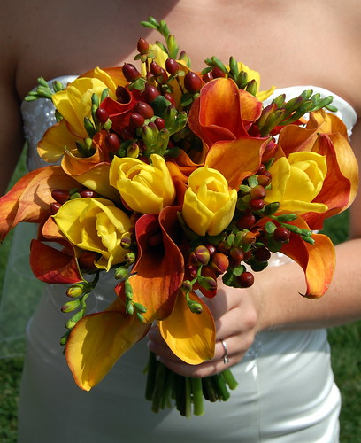 The bride is carrying a large bouquet of flame calla lilies tulips 