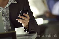 Young urban business man messaging using blackberry pda cell phone. by Brownstock