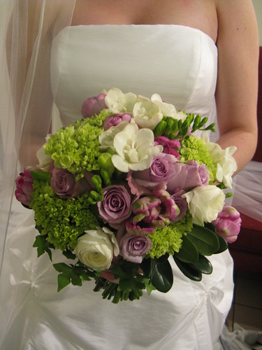 Here's a lovely bouquet with purple roses and green and white flowers 