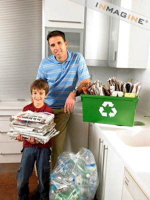 Father and son (6-8) in kitchen with recycling, smiling