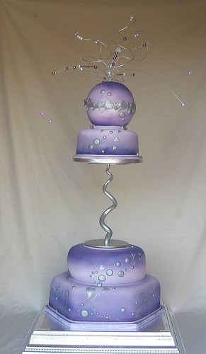 This four tiered purple wedding cake has thin wired beading headdress coming