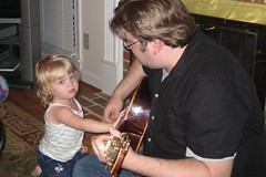 Cate helping her daddy play guitar