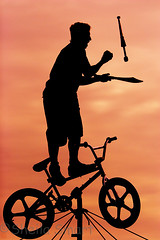 Busker on tightrope with bicycle silhouette