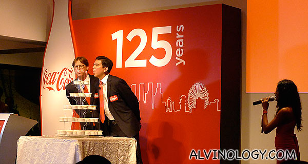 Two Coca-Cola top management staff blowing a birthday cake