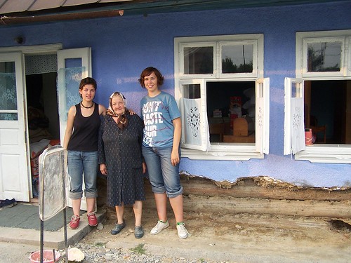Valya and Olya with a woman outside of her damaged home