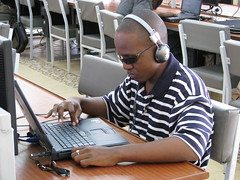 A visually impaired student in Kenya using a laptop equipped with a Dolphin Pen, which magnifies and reads computer screens by DFID - UK Department for International Development