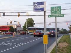 Bicycle route sign pointing to the Twinbrook Metro and a RideOn bus stop sign and a RideOn bus