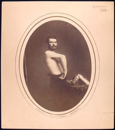 [Shirtless man stands sideways displaying right forearm, bra... by New York Public Library
