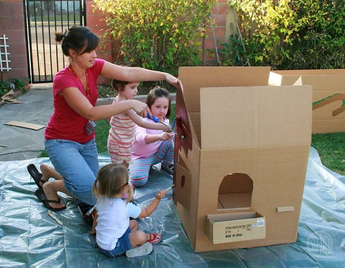 Women and kids painting life size cardboard gingerbread house 