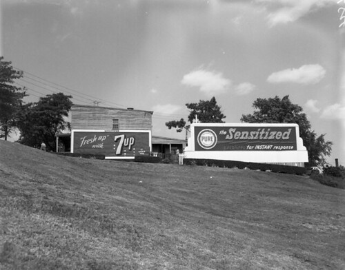 Billboard advertisements for 7Up and Pure gasoline