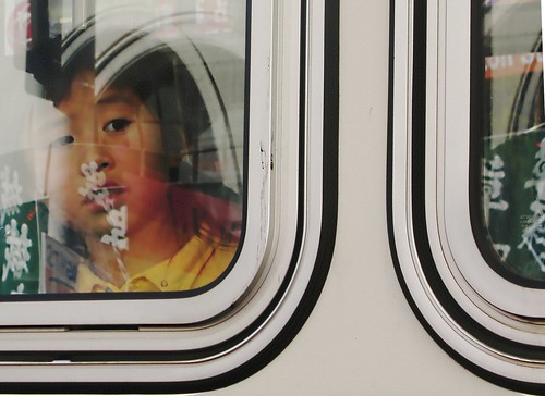 Child looking out of bus at city reflections