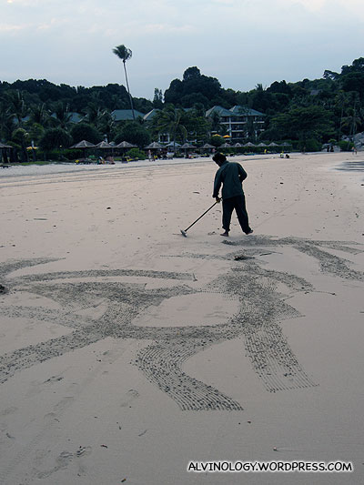 Resort staff raking the sand