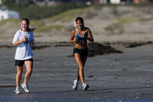 Two young girls jog along Morro Strand State Beach - Ethnic Diversity depicted