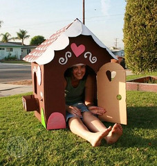 Life size gingerbread house painted and decorated with a woman sitting inside 