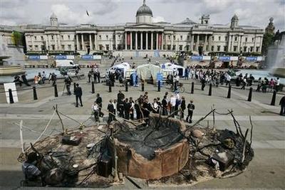 School pupils look at a representation of a Darfur village supposedly destroyed during the war, in central London's Trafalgar Square, build by UNHCR as part of global commemorations of World Refugee Day later this week