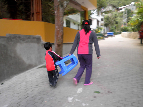 niño ayuda a llevar sillas sin necesidad