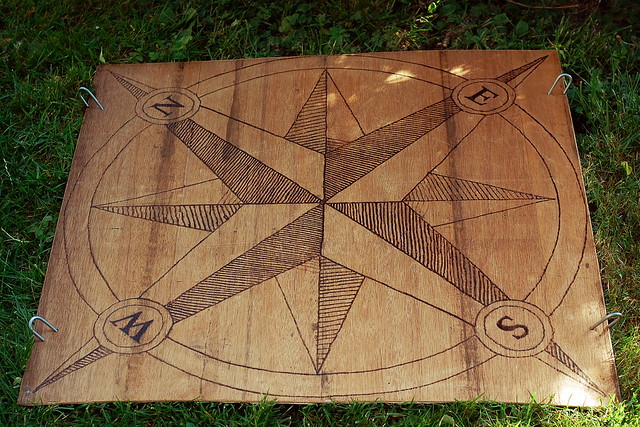 Old fashioned style fixed compass, burned into a sheet of plywood