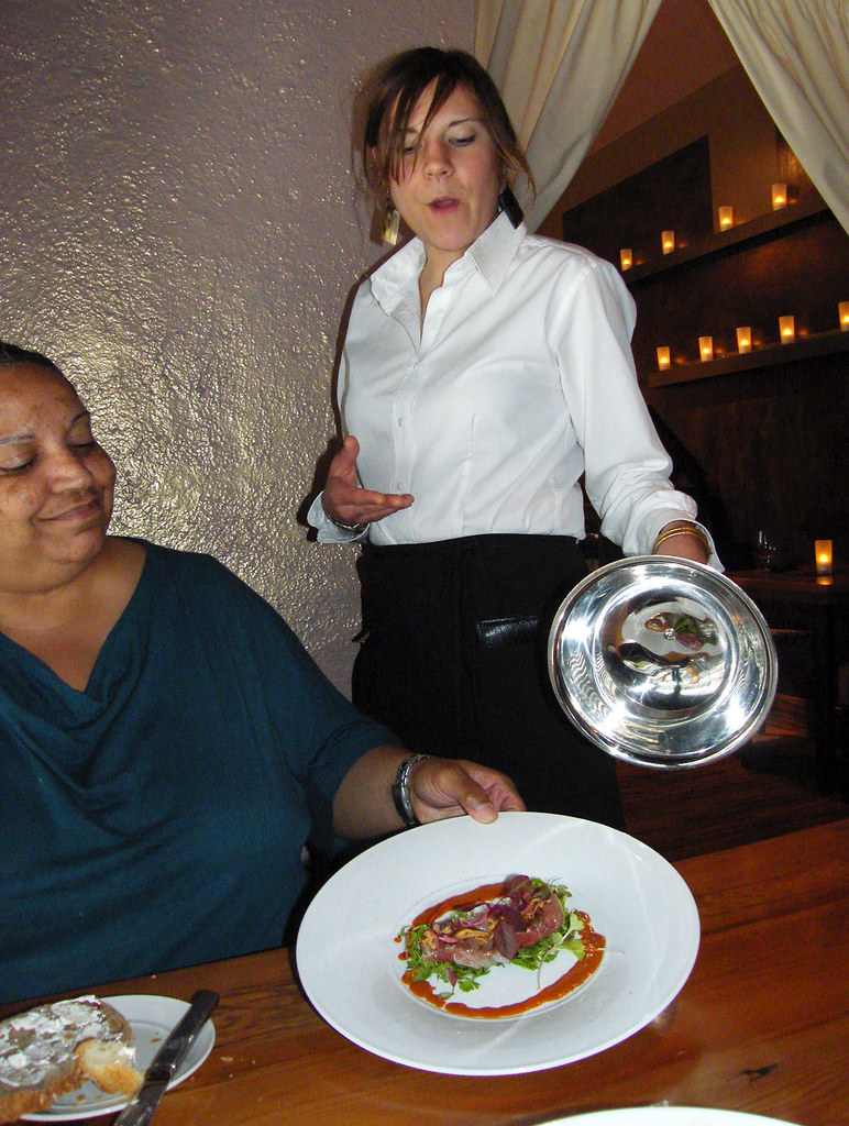 A server at Heidi's presents a dish to Carole