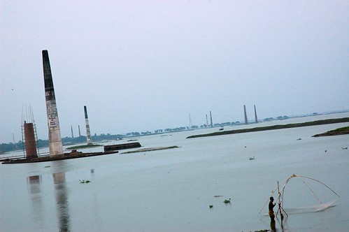 Netting fish on the Turag River, with the brickworks stacks in the distance, Dhaka, Bangladesh by Wonderlane
