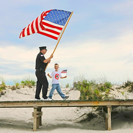 4th of July boardwalk parade led by Fireman and son in Davis Park, Fire Island