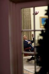 President Barack Obama tosses a football in the Oval Office.