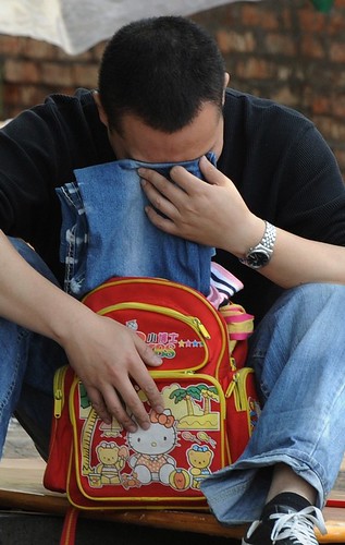 A father cries holding the clothes of his child. Photo from http://www.daylife.com/photo/0fNrfsrfKw7ke