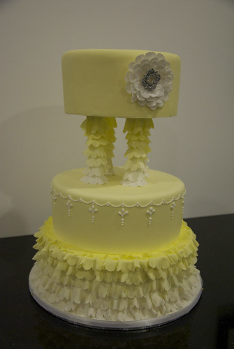A frilly yellow and white wedding cake adorned with an edible sparkling 