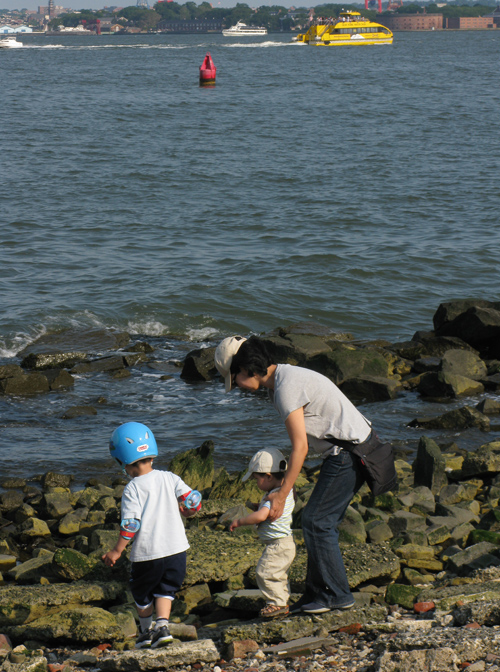 a kid wears a helmet on the shore of the Hudson River