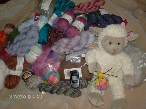 Joy's yarn stash with Sheepy the toy sheep and my knitted sock in front of my yarn stash