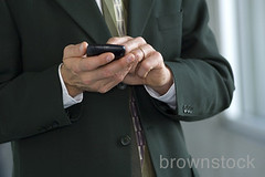 Business man messaging on blackberry pda cell phone. by Brownstock