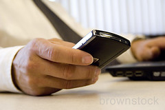 Business man messaging using blackberry pda cell phone in office. by Brownstock