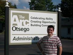 Justin standing on the front of The Arc Otsego's billboard