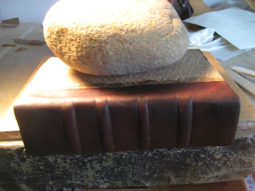 Leather spine drying under a weight