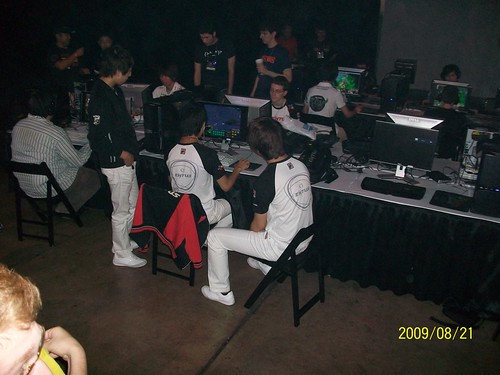The pro-gamer Area. ret (left, striped shirt) plays against EffOrt surrounded by watching teammates SaviOr and sKyHigh.